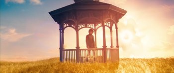 Movie still from “The Lovely Bones” (2009), directed by Peter Jackson – A person sitting in a gazebo on top of a grass covered field; Wide shot, Low angle