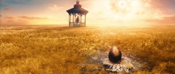 Movie still from “The Lovely Bones” (2009), directed by Peter Jackson – A person sitting in the grass near a gazebo; Extreme Wide shot, High angle