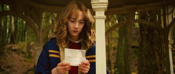 Movie still from “The Lovely Bones” (2009), directed by Peter Jackson – A young girl holding a piece of paper in front of her face; Close Up shot, Over the shoulder angle