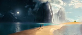 Two people walking on the beach near a waterfall