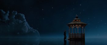 Movie still from “The Lovely Bones” (2009), directed by Peter Jackson – A person standing in the water near a gazebo at night; Extreme Wide shot, Low angle