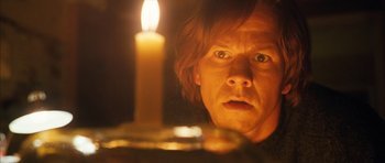 Movie still from “The Lovely Bones” (2009), directed by Peter Jackson – A man staring at a candle in the dark; Close Up shot, Low angle