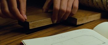 Movie still from “The Lovely Bones” (2009), directed by Peter Jackson – A person is working on a piece of wood on a table; Extreme Close Up shot, Overhead angle