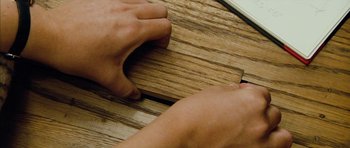 Movie still from “The Lovely Bones” (2009), directed by Peter Jackson – A person sanding a piece of wood on top of a table; Extreme Close Up shot, Overhead angle