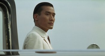Movie still from “The Lover” (1992), directed by Jean-Jacques Annaud – A man in a white suit and a brown tie; Close Up shot, Low angle