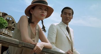 Movie still from “The Lover” (1992), directed by Jean-Jacques Annaud – A man and a woman standing next to a railing; Medium shot, Low angle