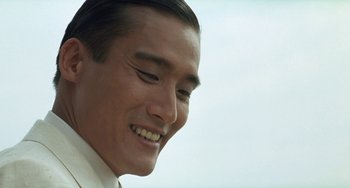 Movie still from “The Lover” (1992), directed by Jean-Jacques Annaud – A man's face with a smile; Close Up shot, Low angle