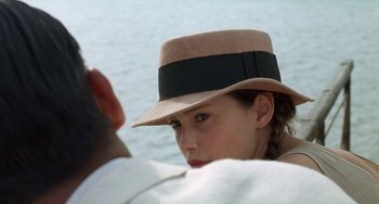 Movie still from “The Lover” (1992), directed by Jean-Jacques Annaud – A young woman wearing a hat looking at a man; Close Up shot, Over the shoulder angle
