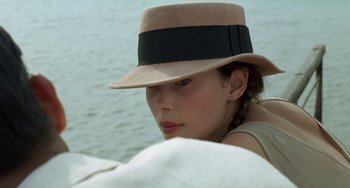 Movie still from “The Lover” (1992), directed by Jean-Jacques Annaud – A young woman wearing a hat on top of a sailboat; Close Up shot, Over the shoulder angle