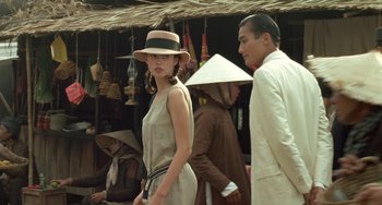 Movie still from “The Lover” (1992), directed by Jean-Jacques Annaud – A woman wearing a hat and a dress; Medium shot, Over the shoulder angle