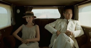 Movie still from “The Lover” (1992), directed by Jean-Jacques Annaud – A man and a woman sitting in the back of a car; Medium shot, Low angle