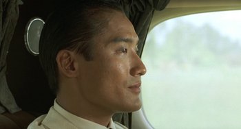 Movie still from “The Lover” (1992), directed by Jean-Jacques Annaud – A person sitting in a car; Close Up shot, Low angle