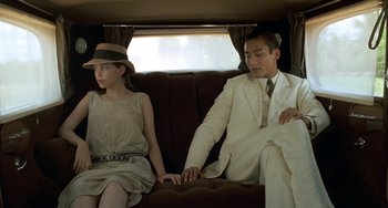 Movie still from “The Lover” (1992), directed by Jean-Jacques Annaud – A man and a woman sitting on a couch; Medium shot, Over the shoulder angle