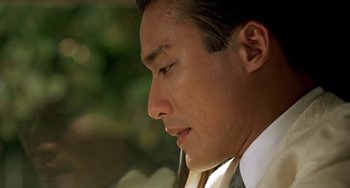 Movie still from “The Lover” (1992), directed by Jean-Jacques Annaud – A person wearing a suit and tie; Close Up shot, Low angle
