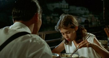 Movie still from “The Lover” (1992), directed by Jean-Jacques Annaud – A woman and a man are sitting at a dinner table; Close Up shot, Over the shoulder angle
