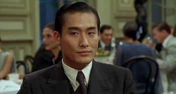 Movie still from “The Lover” (1992), directed by Jean-Jacques Annaud – A person wearing a suit and tie; Close Up shot, Low angle