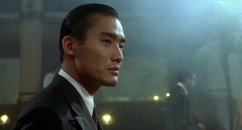 Movie still from “The Lover” (1992), directed by Jean-Jacques Annaud – A person wearing a suit and tie; Close Up shot, Low angle