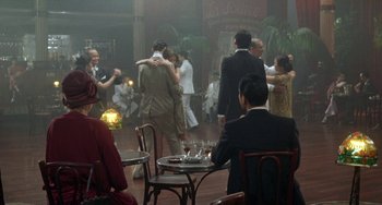 Movie still from “The Lover” (1992), directed by Jean-Jacques Annaud – A group of people dancing in an indoor area; Wide shot, High angle