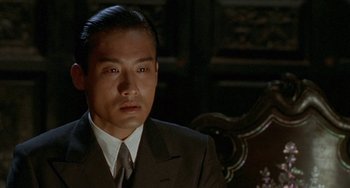 Movie still from “The Lover” (1992), directed by Jean-Jacques Annaud – A person wearing a suit and tie; Close Up shot, Low angle