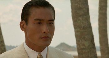 Movie still from “The Lover” (1992), directed by Jean-Jacques Annaud – A person wearing a suit and tie; Close Up shot, Over the shoulder angle