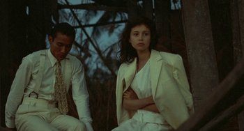 Movie still from “The Lover” (1992), directed by Jean-Jacques Annaud – A man and a woman sitting next to each other; Medium shot, High angle
