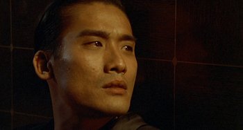 Movie still from “The Lover” (1992), directed by Jean-Jacques Annaud – A man's face in a dark room; Close Up shot, Low angle