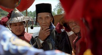 Movie still from “The Lover” (1992), directed by Jean-Jacques Annaud – An older man wearing a hat and a black robe; Close Up shot, Low angle
