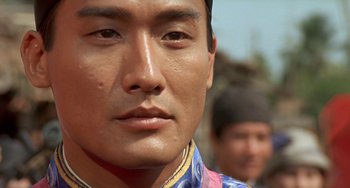 Movie still from “The Lover” (1992), directed by Jean-Jacques Annaud – A man's face in front of another man; Close Up shot, Over the shoulder angle