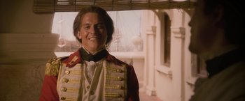 Movie still from “The Lovers” (2015), directed by Roland Joffé – A man in a red and white jacket smiling; Medium shot, Low angle