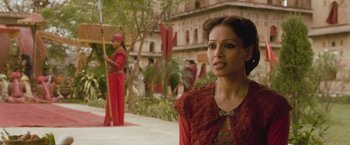 Movie still from “The Lovers” (2015), directed by Roland Joffé – A woman in a red dress standing in front of a building; Medium shot, Over the shoulder angle