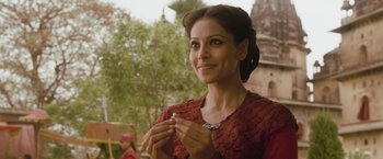 Movie still from “The Lovers” (2015), directed by Roland Joffé – A woman in a red dress is holding something in her hands; Close Up shot, Over the shoulder angle