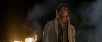 Movie still from “The Lovers” (2015), directed by Roland Joffé – A man standing in front of a fire at night; Close Up shot, Over the shoulder angle