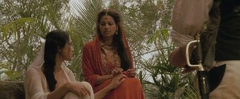 Movie still from “The Lovers” (2015), directed by Roland Joffé – A woman in an orange dress is holding her hands; Medium shot, Over the shoulder angle