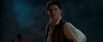 Movie still from “The Lovers” (2015), directed by Roland Joffé – A man in a brown vest standing in front of a tree; Close Up shot, Over the shoulder angle