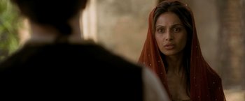 Movie still from “The Lovers” (2015), directed by Roland Joffé – A woman with a red head covering looking at a man in a black suit; Close Up shot, Over the shoulder angle