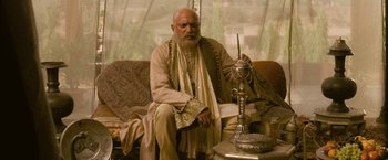 Movie still from “The Lovers” (2015), directed by Roland Joffé – An older man sitting on a couch with a candle; Medium shot, Low angle