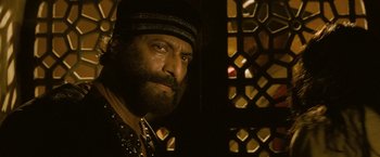 Movie still from “The Lovers” (2015), directed by Roland Joffé – A man with a long beard and a hat; Close Up shot, Over the shoulder angle