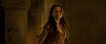 Movie still from “The Lovers” (2015), directed by Roland Joffé – A woman with long dark hair standing in a dark room; Medium shot, Low angle