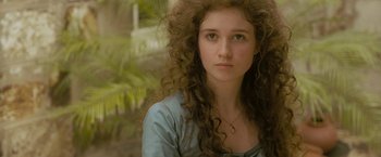 Movie still from “The Lovers” (2015), directed by Roland Joffé – A woman with long curly brown hair wearing a blue shirt; Close Up shot, High angle