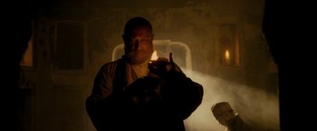 Movie still from “The Lovers” (2015), directed by Roland Joffé – A man lighting a candle in a dark room; Medium shot, Low angle