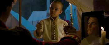 Movie still from “The Lovers” (2015), directed by Roland Joffé – A young boy is holding a candle in his hand; Close Up shot, Over the shoulder angle