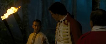 Movie still from “The Lovers” (2015), directed by Roland Joffé – A man in a red and white uniform standing next to a boy in a white shirt; Medium shot, Over the shoulder angle