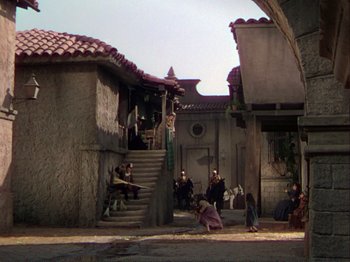 Movie still from “The Loves of Carmen” (1948), directed by Charles Vidor – A group of people sitting on steps near a building; Extreme Wide shot, High angle