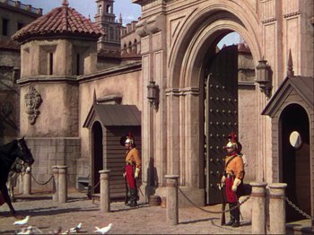 Movie still from “The Loves of Carmen” (1948), directed by Charles Vidor – A painting of two men standing in front of an entrance to a building; Wide shot, High angle