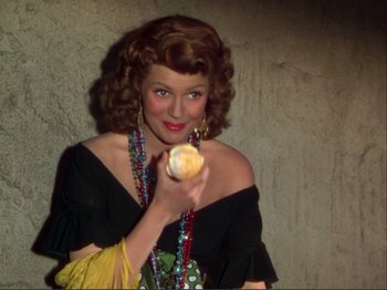 Movie still from “The Loves of Carmen” (1948), directed by Charles Vidor – A woman holding an orange in her hand; Medium shot, Overhead angle