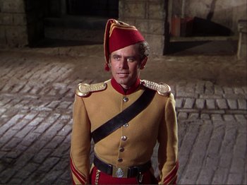 Movie still from “The Loves of Carmen” (1948), directed by Charles Vidor – A man in a red and yellow uniform standing on a street; Medium shot, High angle