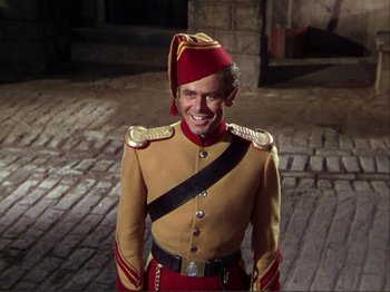 Movie still from “The Loves of Carmen” (1948), directed by Charles Vidor – A man dressed in a military uniform smiling for the camera; Medium shot, High angle