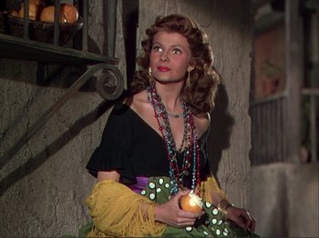 Movie still from “The Loves of Carmen” (1948), directed by Charles Vidor – A woman holding an apple and wearing a necklace; Medium shot, Low angle