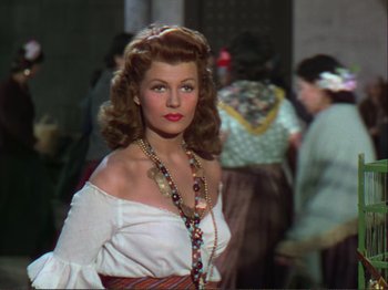 Movie still from “The Loves of Carmen” (1948), directed by Charles Vidor – A woman in a white shirt and a long necklace; Medium shot, Low angle