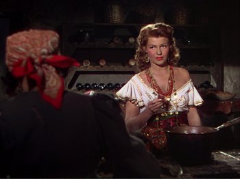 Movie still from “The Loves of Carmen” (1948), directed by Charles Vidor – A woman is cooking in a kitchen wearing a red bandana; Medium shot, Over the shoulder angle